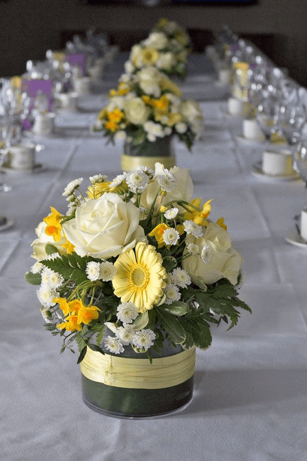 Yellow and white flowers as centrepiece in yellow bucket